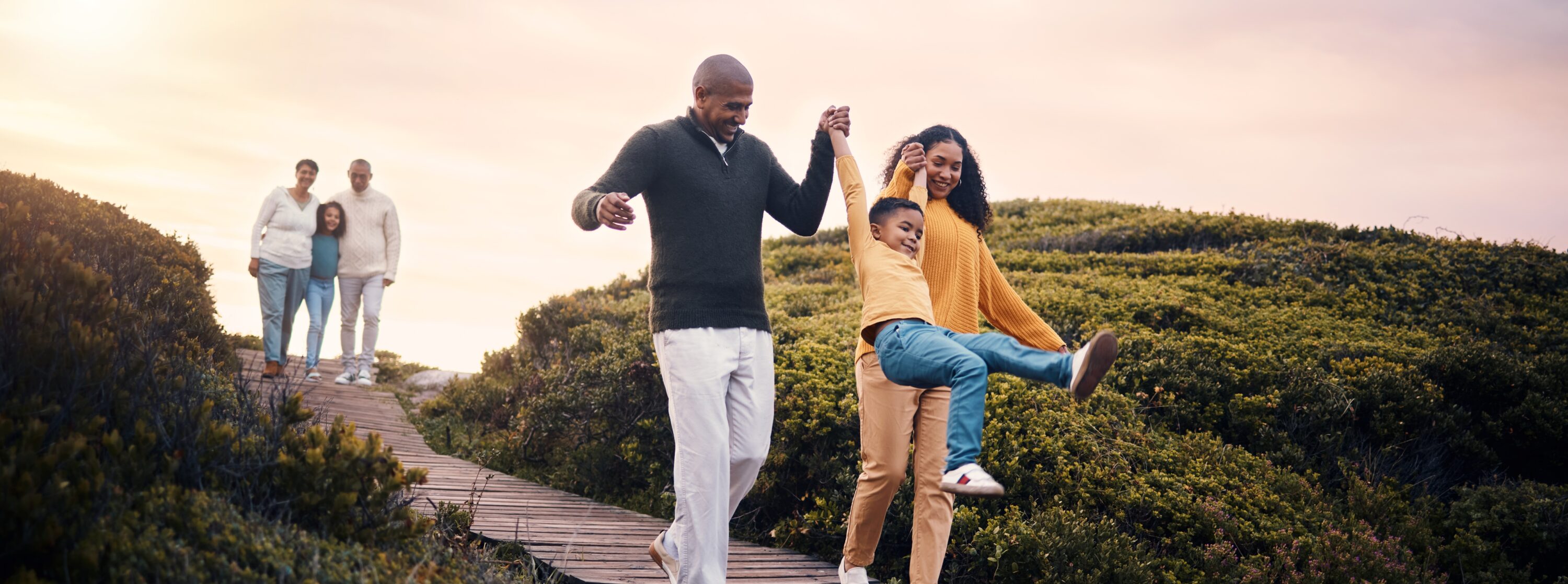 Young black man and woman with young boy with older grandparents in the background with daughter